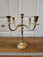 Front view of brass five-arm candelabra on table with ruler for scale