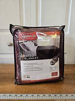 Front view of packaged Sunbeam heated blanket showing branding, size and color