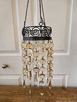 Full view of tealight holder hanging, showing metal frame and strands