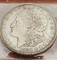 Front obverse face of 1921 D Morgan Dollar showing Liberty profile and date 1921, exhibiting wear and surface marks.