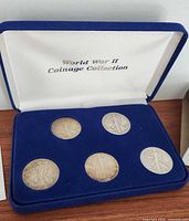 Five silver Walking Liberty half dollar coins displayed in blue velvet case labeled 'World War II Coinage Collection'.