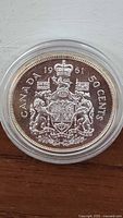 Reverse view of the coin showing detailed Canadian coat of arms, date 1961 and denomination '50 CENTS' in protective case.