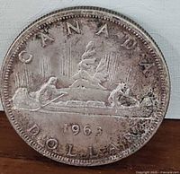 Obverse side of the 1963 Canadian silver dollar coin showing the canoe design with the year 1963 and inscriptions "CANADA" and "DOLLAR".