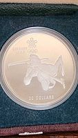 Close-up of ski jumper side of silver coin with Calgary 1988 and Olympic rings.