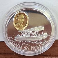 Obverse side showing Vickers Vedette biplane with 24kt gold-covered oval cameo of a man in hat and 'CANADA 20 DOLLARS' inscription.