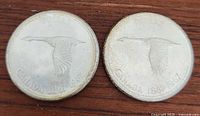 Two Canadian silver dollar coins with flying goose design, date range 1867-1967, showing front sides of both coins.