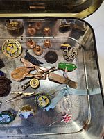 Overview of assorted pins and clutch backs in tin