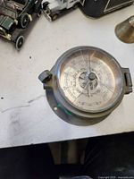 Top view of round brass barometer showing dial and glass