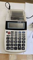 Front view showing Victor 1205-4 calculator with keypad, display, print mechanism and attached AC cord