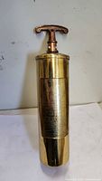 Full view of brass fire extinguisher refill cylinder with T-handle