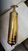 Full view of brass fire extinguisher lying flat