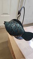 Left side view of teal metal fish candle lantern showing cut-out scales