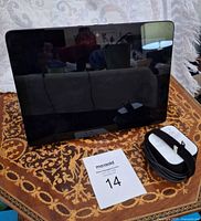 Front view of Amazon Echo Show with screen off and power adapter beside