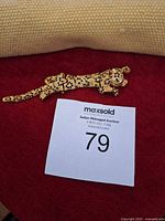 Leopard brooch front view on red fabric showing overall design and black enamel spots