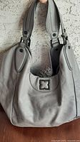 Front and side view of grey BCBGMAXAZRIA handbag