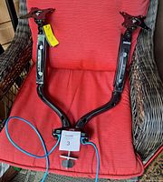 Front view of dual monitor mount on chair showing arms, VESA plates, base with USB cables