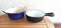Blue casserole and black fondue pot side by side on table