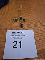 Ring, pendant on chain, stud earrings laid out on wood surface