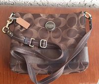 Front view of Coach brown signature jacquard crossbody purse showing logo plaque, strap and trim