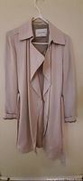 Full view of front of Babaton beige trench coat on hanger
