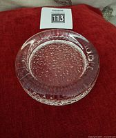 Top view of round clear glass ashtray showing smooth interior and textured rim