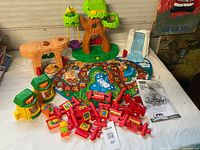 All playset components laid out: tree house, slide, mat, fences, sound blocks, table, manual