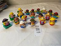 Full group of Little People figures and vehicles laid out on white surface