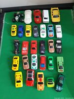 Top view of full assortment of 26 toy vehicles on green surface