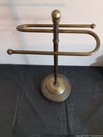 Front view of brass-tone necklace stand showing base and arms