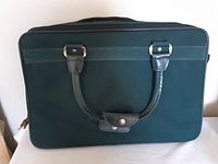 Front view of green canvas suitcase with dual handles