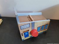 Front and top of wooden garage building showing red knob, blue door, windows