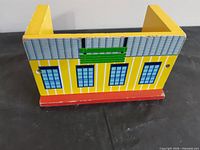 Front view of yellow wooden hospital with blue windows and green sign