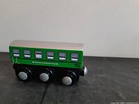 Left side view of green wooden passenger car #721 with three wheelsets and magnetic coupler