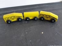 Three yellow wooden train cars aligned side by side