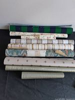 Stacked view of striped canvas piece and seven wallpaper rolls