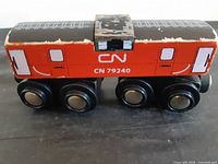 Left side view of red CN 79240 wooden boxcar showing logo and wheels