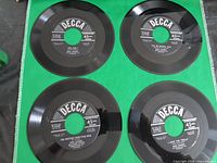 All four Decca 45s displayed label-up on green background