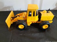 Right-side view of yellow toy bulldozer showing blade and wheels