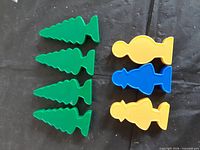 Six green tree models and three people figures arranged on black surface