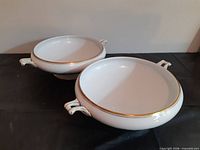 Two matching white porcelain serving bowls with gold trim