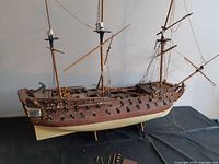 Full view of partially built wooden warship model, showing hull, masts and rigging
