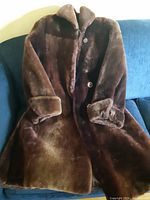 Full view of brown mouton fur coat on sofa