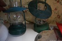 Angled view of both lantern lamps on shelf showing bases, globes and handles