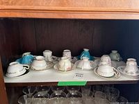 Twelve inverted teacups with saucers on cabinet shelf
