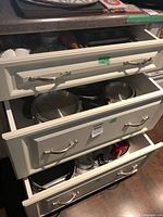 Drawers showing stainless pots, utensils, mixer and additional items