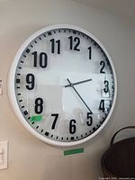 Front view of white round wall clock displaying black numerals and hands with glass front