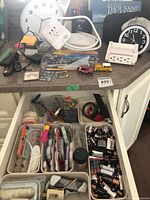Countertop view with clocks, power adapters, pens, toy vehicles, magnets