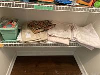 Shelf with folded linens and green plastic box