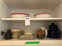 Cabinet shelf displaying all nine ceramic and stoneware pieces