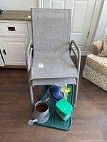 Two stacked grey metal frame patio chairs with garden supplies on green tray